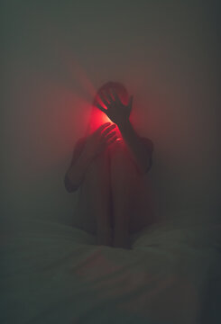 Hands covering a red light coming from the mouth