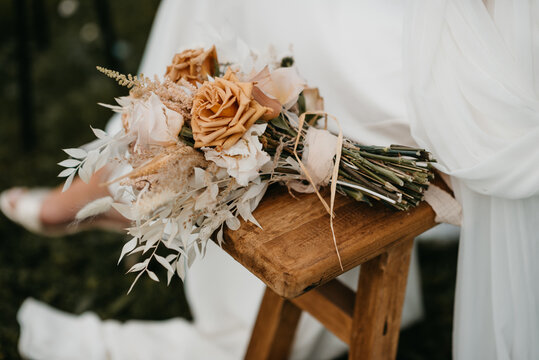 Autumn wedding bouquet on a bench next to bride