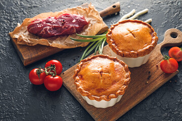 Tasty beef pot pies with meat on dark background