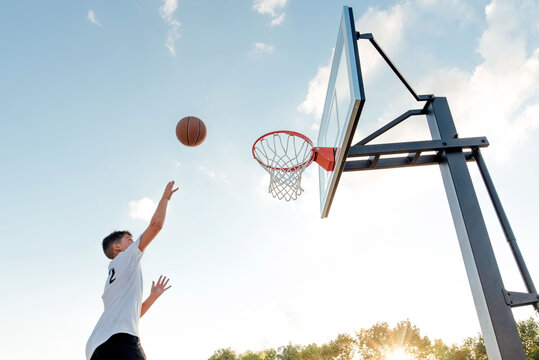 Teen boy playing basketball on a beautiful day. 