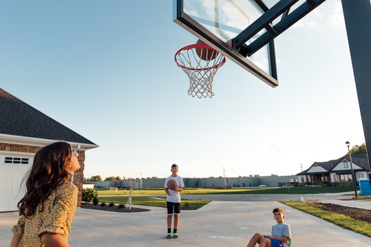 Kids watching a basketball being shot at rim. 