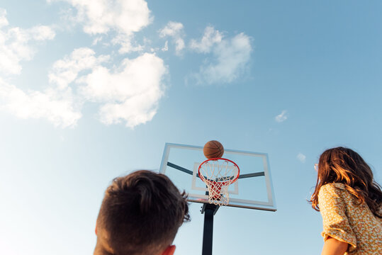 Back of two teenagers looking at basketball backboard. 