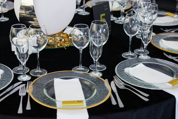 Restaurant interior, black tables with transparent plates and a golden cutlery. High quality photo