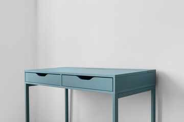 Blue desk with drawers near light wall