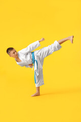 Fototapeta na wymiar Little boy practicing karate on color background