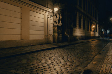 view of a dark and illuminated cobblestone street in the old town of prague at night 2021