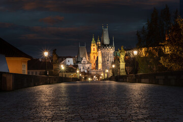 old cobbled sidewalk with paving Charles Bridge in the center of Prague and in the background the old bridge tower at night in the Czech Republic and the light from street lighting