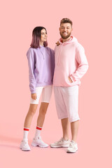 Cool young couple in hoodies on color background