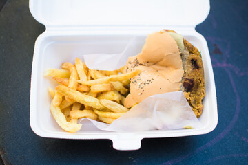 Veggie burger and fries half eating in a to go box