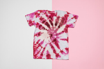 Red and white tie dye T-shirt on a pink and white background. Flat lay.