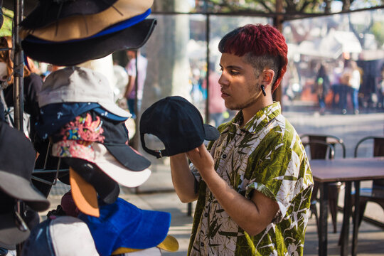Latino young trans man buying a baseball cap