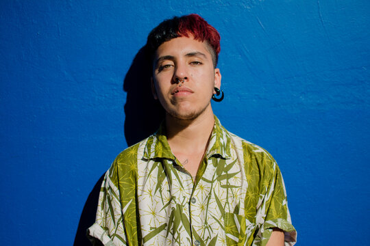 Latino trans man portrait over blue wall