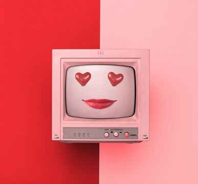 A TV with painted lips and heart-shaped eyes on a red and pink background.