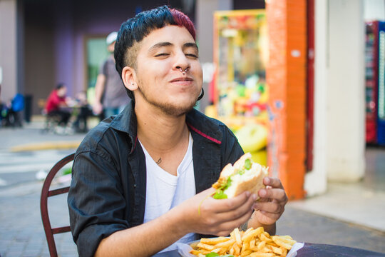 Latino gen z laughing while eating a comfort food