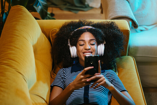 Happy woman using smartphone on sofa
