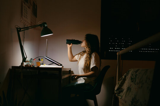 Teen girl drinking water on the desk at study room