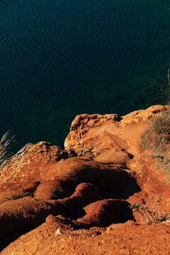 Detail of red soil on water of little lake