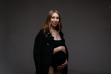 Fototapeta premium a pregnant woman in a black suit and a black hat. Space for copying. The concept of healthy digestion, lifestyle, IVF