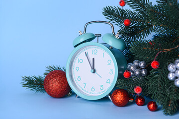 Fototapeta na wymiar Christmas composition with alarm clock, balls and fir branches on blue background