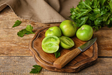 Board with green tomatoes and parsley on wooden background