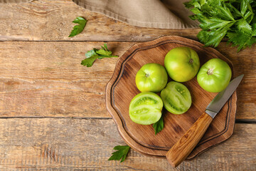 Board with green tomatoes and parsley on wooden background
