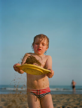 A 3 years old child playing with a sand on a beach