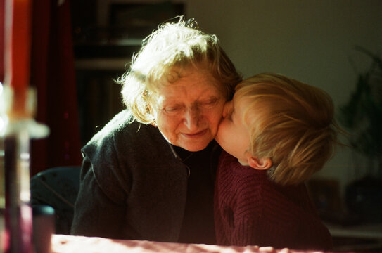 A grandchild kissing his granny