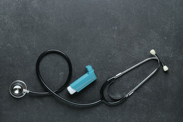 Asthma inhaler and stethoscope on dark background