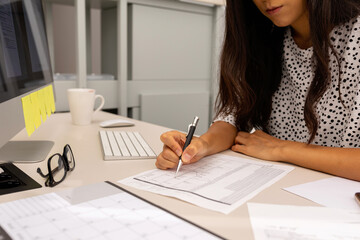 Female writing on documents in office