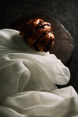 Cinnamon roll with white cloth on a wooden table. Gourmet and bakery concept. Vertical photo.