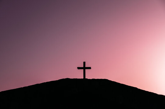Cross on hill against sunset sky