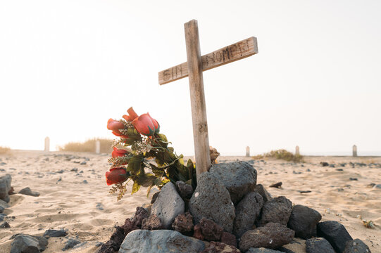 Tomb with wooden cross and flowers in beach