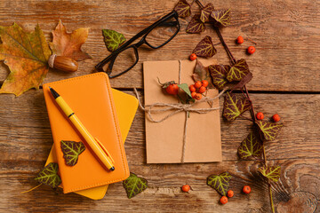 Notebooks with pen, card, eyeglasses, berries and leaves on wooden background