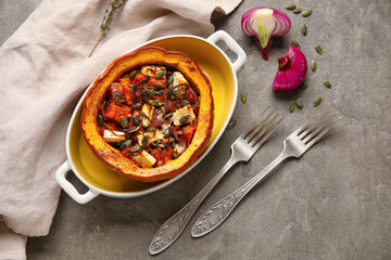 Baking dish with tasty stuffed pumpkin on grey background