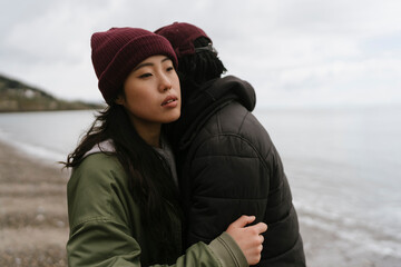 Thoughtful Young Couple Hugging on the Beach 