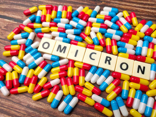 Phill capsule and toys word with word OMICRON on a wooden background.