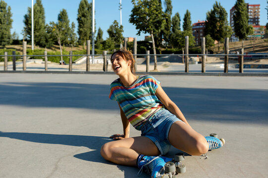 Roller-skater girl on ground laughing after falling