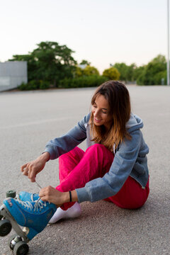 Young cheerful woman getting ready to roller-skating