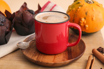 Cup of tasty pumpkin coffee on beige background