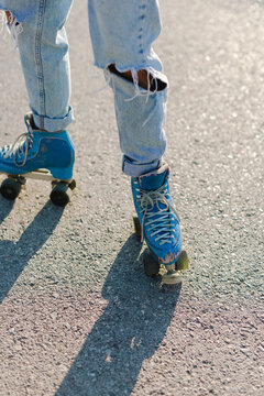 Roller-skater's legs with old blue skates in sunlight