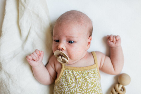 Newborn baby girl with rattle and pacifier