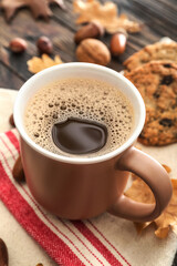 Cup of coffee with acorns on table, closeup