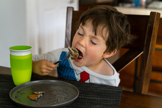 A young boy eating blueberry pancakes