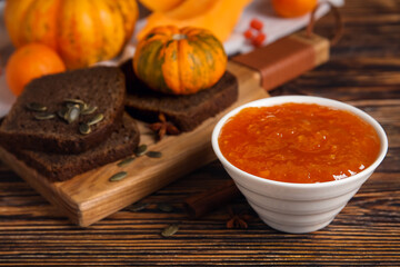 Bowl of sweet pumpkin jam on wooden background