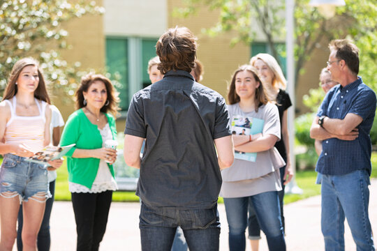 Tour: Rear View Of Guide Talking To Group Of Students And Parent