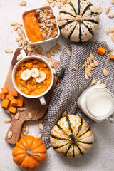 Fototapeta na wymiar Pot and bowl of tasty oatmeal with pumpkin on white background