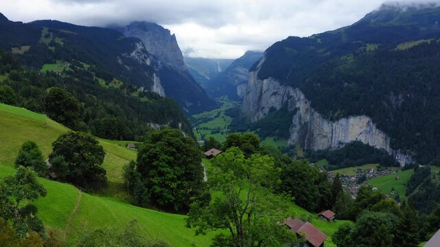 Aerial Forward Residential Houses On Green Landscape In Village Amidst Mountains - Lauterbrunnen, Switzerland