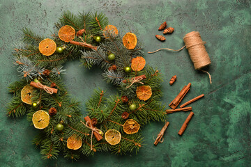 Obraz na płótnie Canvas Beautiful Christmas wreath made of fir branches and cinnamon on green background