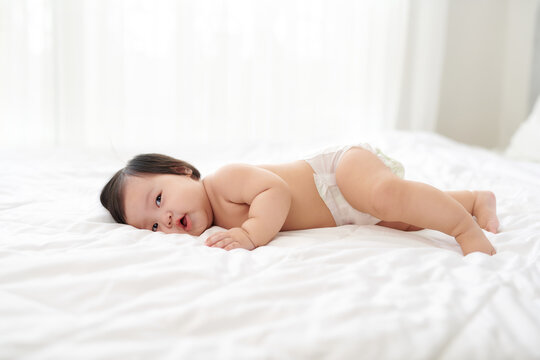Cute smiling baby lying on white towel in nappy