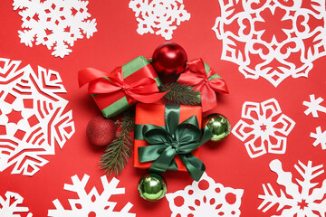 Gift boxes, Christmas balls and paper snowflakes on red background